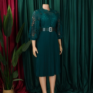 Detail of dark green pleated dress featuring lace embroidery and metal buckle belt