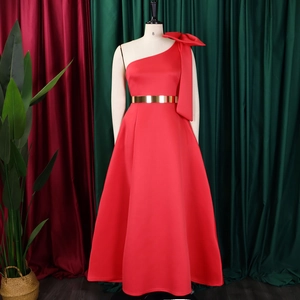 Detail of red one-shoulder evening gown featuring a large bow and gold mirror belt
