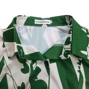 Détail du col rabattu et de l'imprimé feuilles tropicales sur tissu lisse