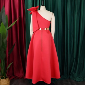 Detail of red one-shoulder gown with oversized bow and gold waist belt with chains