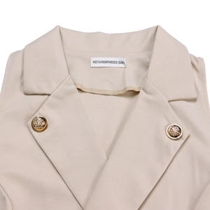 Close-up of beige blazer jumpsuit collar with gold buttons and brand label detail