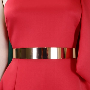Close-up of polished gold mirror metal waist belt on a red one-shoulder evening dress