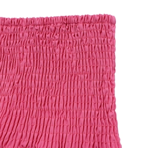 Détail du tissu froncé rose vif avec texture élastique sur l'ensemble haut et pantalon