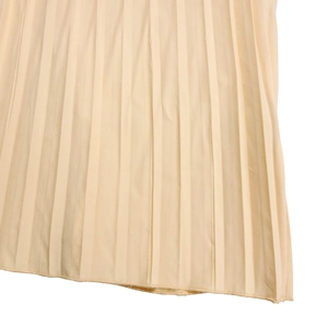 Détail du tissu plissé beige montrant les plis accordéon verticaux et l'ourlet fin