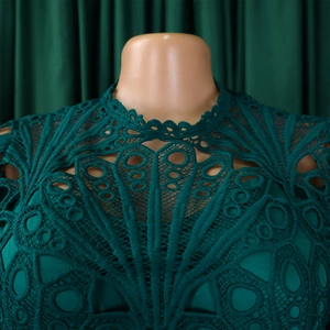Close-up of the elegant dark green lace neckline with intricate hollow-out embroidery detail