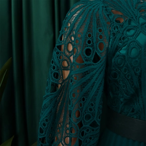 Detailed view of dark green hollow lace sleeve with geometric patterns on dress