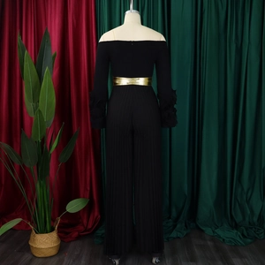Détails du dos d'une combinaison noire à épaules dénudées avec texture plissée et ceinture dorée