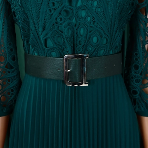 Detailed view of the dark green lace bodice and pleated dress with a D-buckle belt
