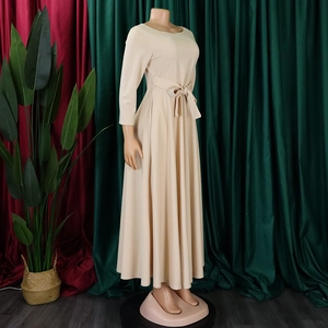 Detail of waist tie knot and pleated A-line skirt on a beige maxi dress with long sleeves