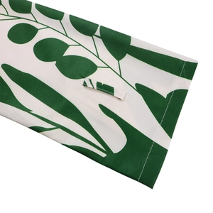Détail de la manche blanche avec imprimé feuilles vertes et patte de boutonnage
