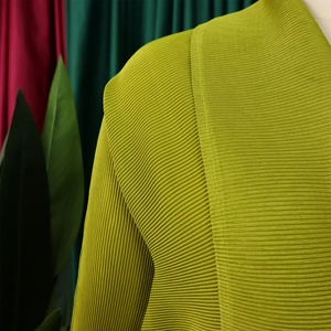 Dettaglio ravvicinato della texture del tessuto plissettato verde lime con pieghe verticali