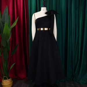 Detail of elegant black one-shoulder dress with bow and golden mirror belt