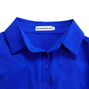 Close-up of vibrant blue long sleeve jumpsuit collar with METAMORPHOSIS GIRL brand label