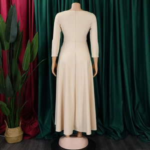 Detail view of high-waist beige A-line dress with wide draped skirt and sash belt