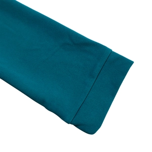 Gros plan détaillé des poignets de manches pliés sur une robe plissée sarcelle