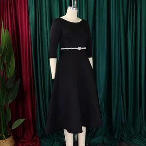 Detail of elegant black midi dress with pearl belt, round neck and flared skirt