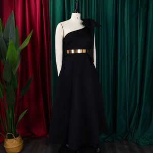Detail of elegant black one-shoulder evening gown with bow accent and gold waist belt