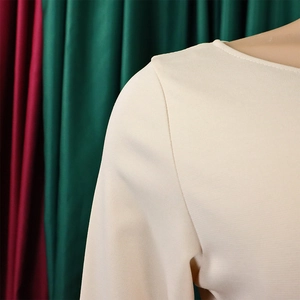 Detailed view of the crew neck and shoulder stitching of this cream woven dress fabric