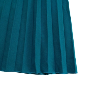 Gros plan sur le tissu plissé vert foncé montrant la texture fine et les coutures soignées