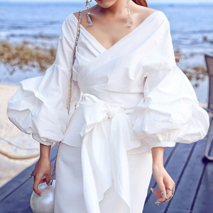 Detail of white wrap shirt with dramatic puff sleeves and large waist bow tie detail