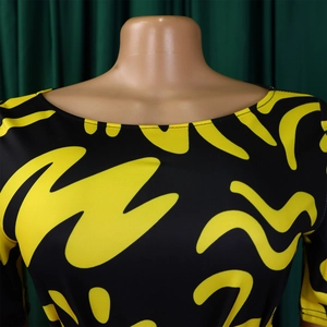 Detail of round neckline and abstract yellow wave print on black African dress fabric