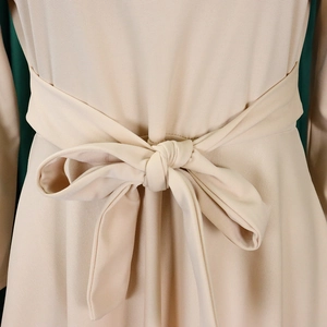 Close-up of a chic beige maxi dress featuring a waist tie with a stylish bow knot