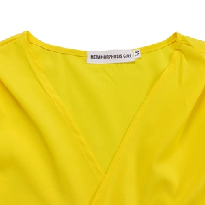 Détail de l'encolure en V croisée et de l'étiquette de taille sur le haut jaune à manches courtes
