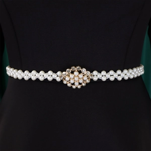 Detail of elegant double-row pearl belt with floral rhinestone buckle on black dress