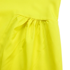 Detail of bright yellow woven dress showing ruffled seams and textured fabric flow