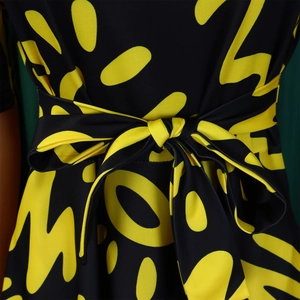 Detail of waist tie bow on African print dress with yellow abstract letter patterns