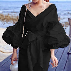 Detail of black off-shoulder wrap top featuring puffed sleeves and waist tie design