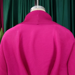 Dettaglio del top a pieghe rosso rosa a collo alto con trama a fisarmonica sul retro