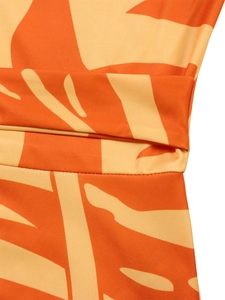 Detailed close-up of orange tropical leaf print fabric with smooth texture and stitching