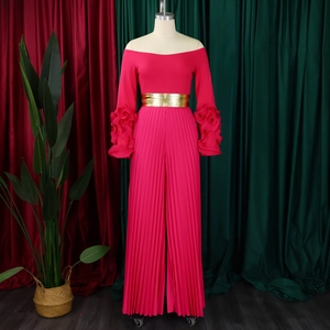 Détail de la combinaison plissée à épaules dénudées rose fuchsia avec ceinture dorée