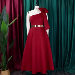 Detail of burgundy one-shoulder gown featuring a large bow and gold metal belt