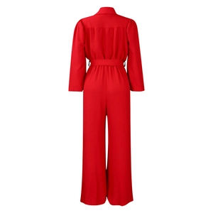 Detail view of red long sleeve jumpsuit with waist belt and wide leg tailoring