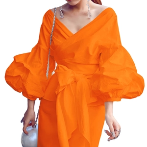 Detail of vibrant orange puff sleeve wrap top with bow tie waist and deep V-neck design