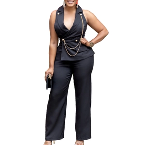 Detail of black jumpsuit showing golden double-breasted buttons and metal chain decor