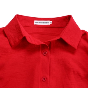 Detail of red long sleeve jumpsuit showing collar texture and button closure on fabric