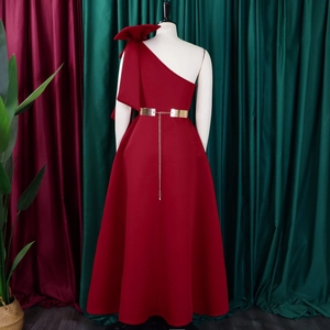 Detail of burgundy one-shoulder gown with oversized bow and golden chain belt
