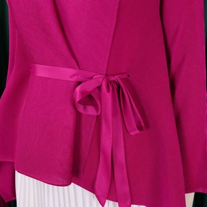 Dettaglio della maglia plissettata fucsia con laccetto in raso e texture 3D in organza