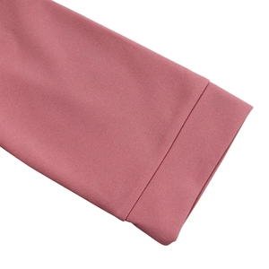 Gros plan du poignet d'une robe rose montrant des coutures précises et la texture du tissu