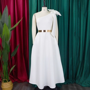 Detail of white one-shoulder evening gown featuring a large bow and gold metal belt