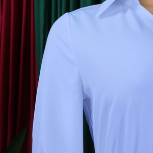 Close-up detail of the elegant white lapel collar and smooth fabric of the pleated dress