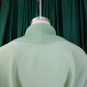 Dettaglio della trama del tessuto plissettato verde chiaro e cuciture del collo sul manichino