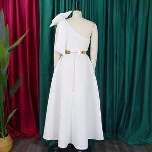 Detail of elegant one-shoulder white gown featuring a large bow and gold metal belt