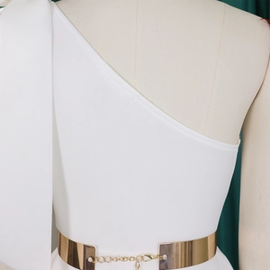 Detail of white one-shoulder dress featuring a polished gold chain waist belt accessory