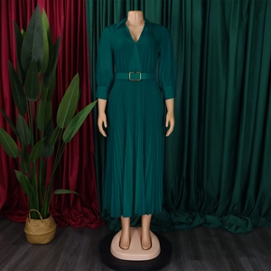 Detail of dark green pleated dress featuring a V-neck and waist belt with golden buckle