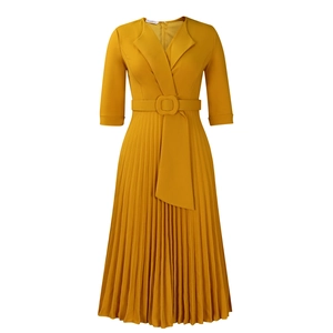 Détail d'une robe plissée jaune moutarde avec col en V, ceinture à boucle et manches 3/4