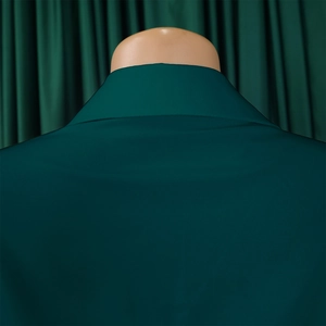 Detail shot of elegant dark green pleated dress neckline with smooth woven fabric texture